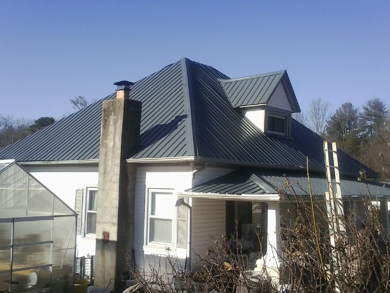 Dark blue standing seam metal roof on a white farmhouse with dormer — Slate & Tile Roof Repair by Roofing Brothers in Jay