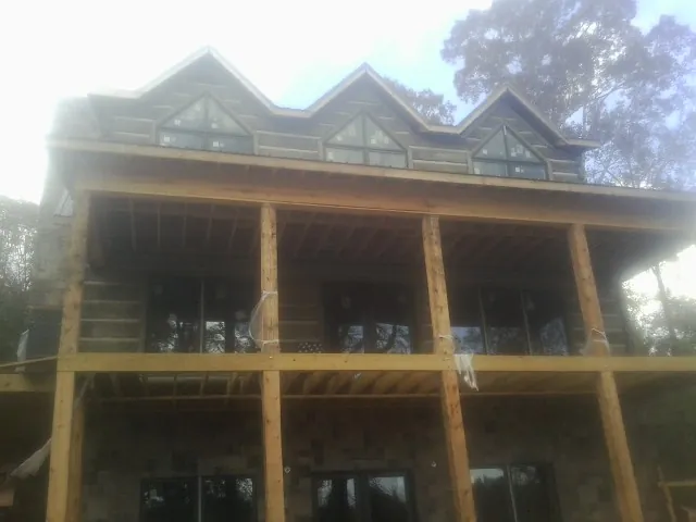 Dormers and porch framing on a large log home under construction — Roof Coating work by our crew in Jay