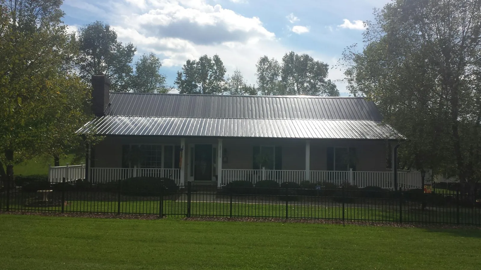 Gray metal roof on a brick ranch with a full width front porch — Gutter Guard Installation work by our crew in Jay
