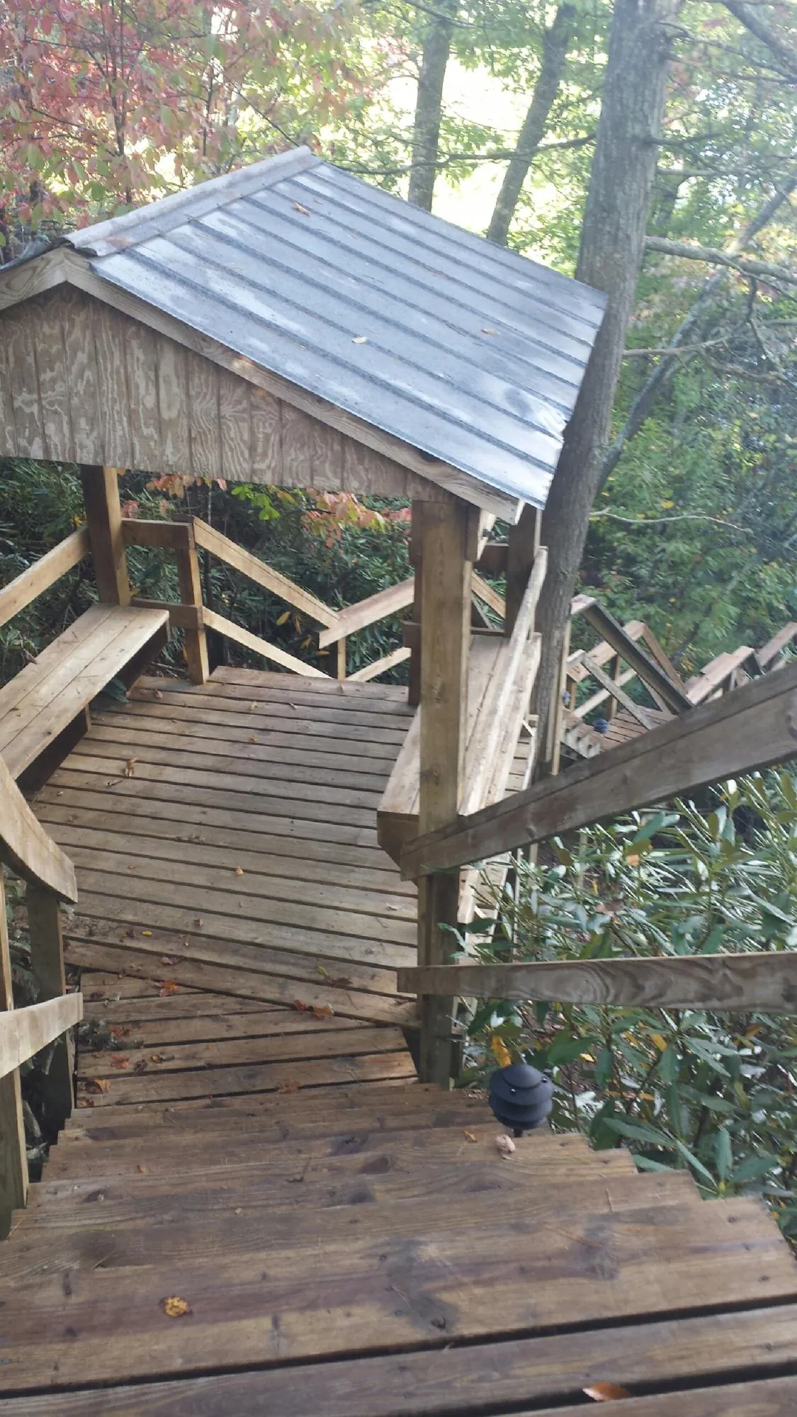 Metal roofed shelter over wooden steps on a wooded walkway — Skylight Repair & Installation work by our crew in Jay